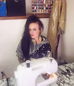 Preguntas y respuestas de GoDaddy con la diseñadora de moda y finalista de Project Runway Kelly Dempsey Kelly sentada en la máquina de coser