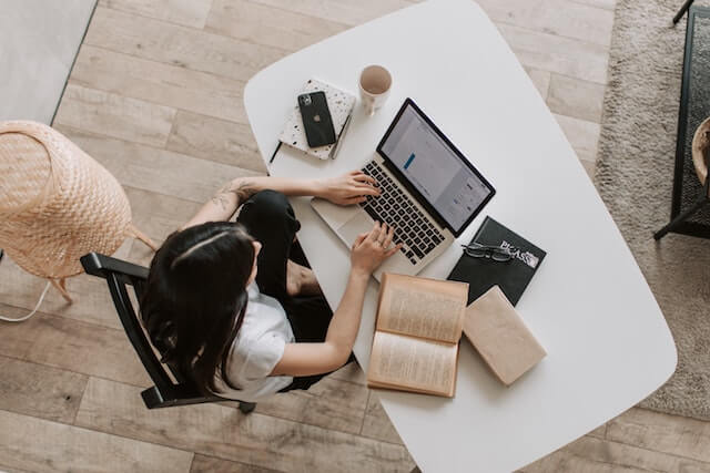Cómo realizar revisiones de empleados Mujer sentada en un escritorio trabajando desde casa