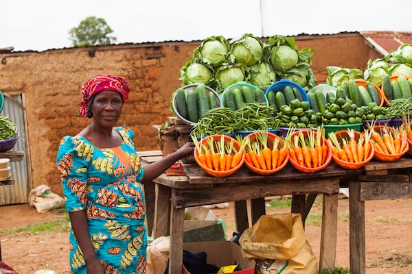 Agricultor nigeriano vendiendo frutas y verduras en el mercado
