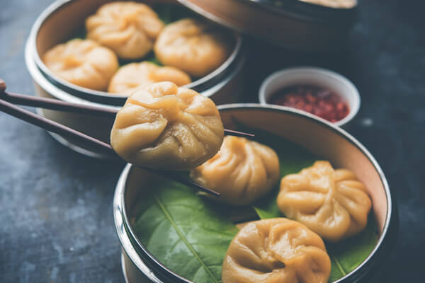 Momos nepaleses con salsa achar en un taz&oacute;n con palillos