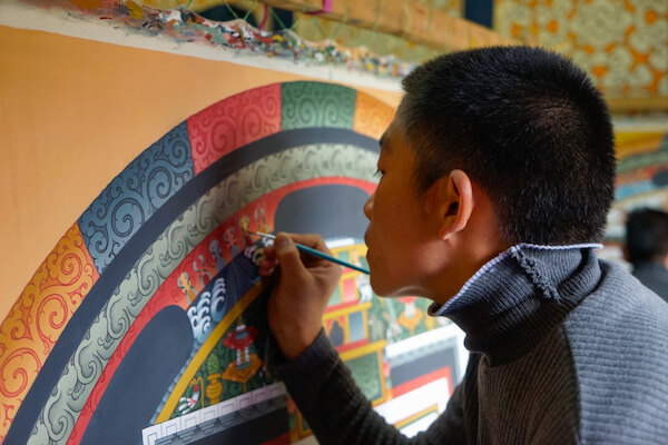 Joven refresca la pintura de un templo de But&aacute;n - imagen de Angela Maier / shutterstock.com