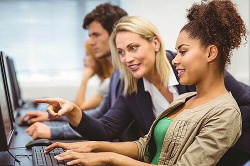 Profesor de marketing apuntando a la pantalla de la computadora de un estudiante durante una lecci&oacute;n sobre texto alternativo