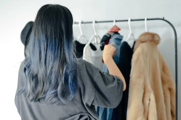 Estilista minorista arreglando abrigos en perchas