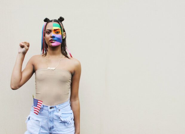 Persona con pintura de la cara de la bandera del orgullo sosteniendo el pu&ntilde;o para el movimiento Black Lives Matter