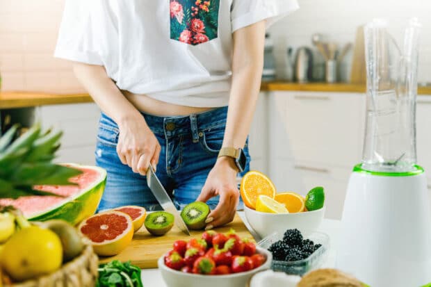 persona en la cocina cortando kiwi y otras frutas