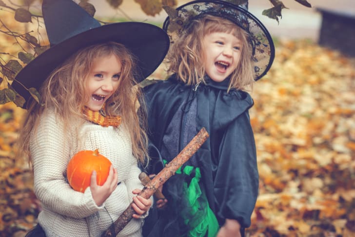 Dos adorables ni&ntilde;as rubias vestidas como brujas para Halloween y sonriendo, una con una calabaza
