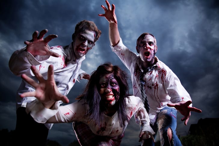 Tres zombies alcanzando al espectador contra un cielo tormentoso