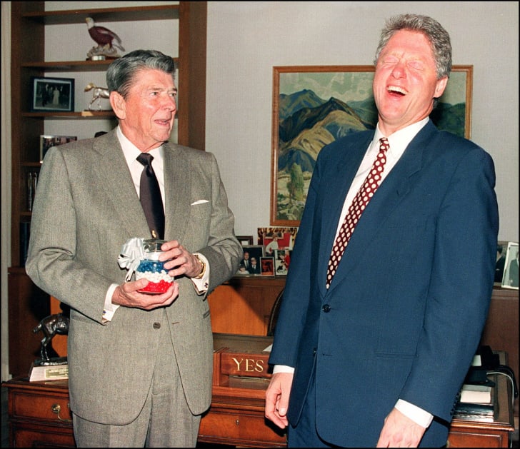 El presidente Ronald Reagan le presenta al presidente electo Bill Clinton un frasco de caramelos rojos, blancos y azules.