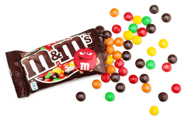 Una bolsa abierta de M & Ms simple sobre un fondo blanco.