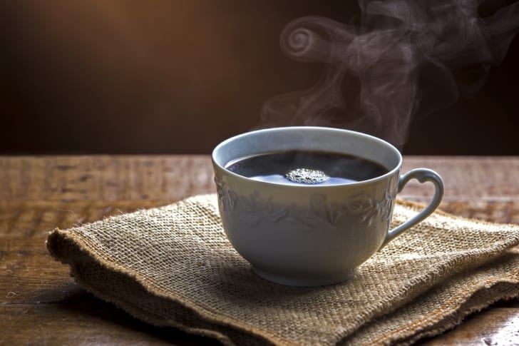 Una taza de caf&eacute; humeante sobre un trozo de arpillera.