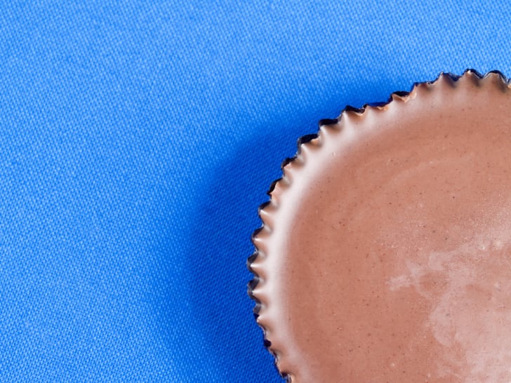 Una foto parcial de una taza de mantequilla de man&iacute; sobre un fondo azul.