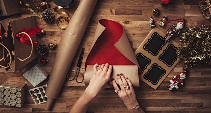 13 consejos para envolver el regalo perfecto de un experto Una imagen de las manos de una mujer envolviendo un regalo de Navidad.