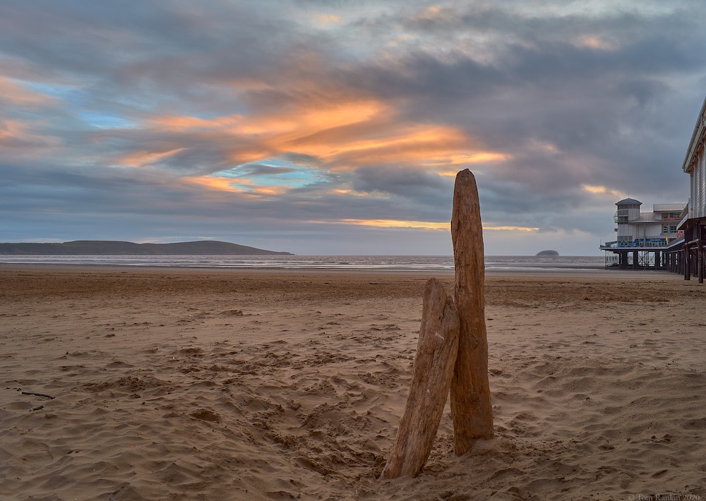 Una imagen de alta calidad que muestra el producto final de la imagen que se muestra en la captura de pantalla anterior de dos bloques de madera flotante en pie en una playa al atardecer, con un alto contraste de color y definici&oacute;n de objetos.