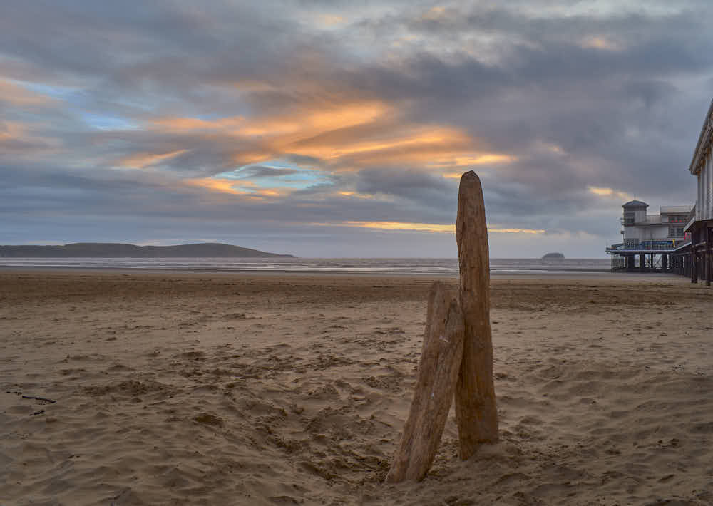 Una imagen de baja calidad que muestra la misma imagen de madera a la deriva en una playa, pero con menor intensidad de color y definici&oacute;n de objeto.
