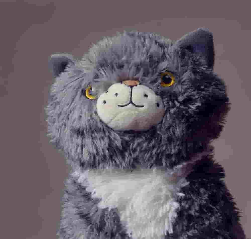 Un retrato de un gato de juguete de peluche, con artefactos evidentes de sobrecompresi&oacute;n, como bandas, elementos no afilados y degradaci&oacute;n.